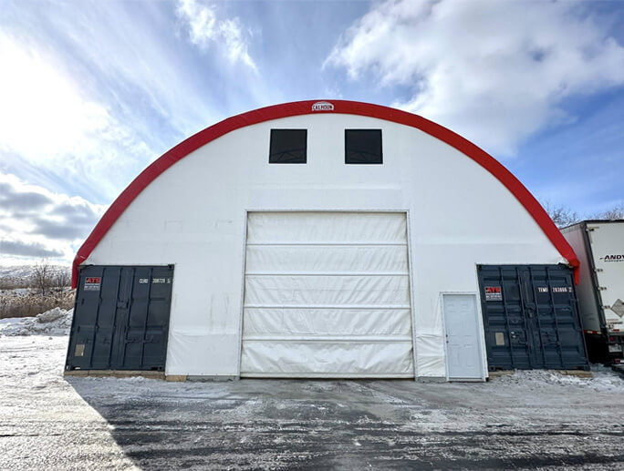 Façade d’un bâtiment en toile avec charpente d’acier galvanisé et porte sectionnelle en hiver