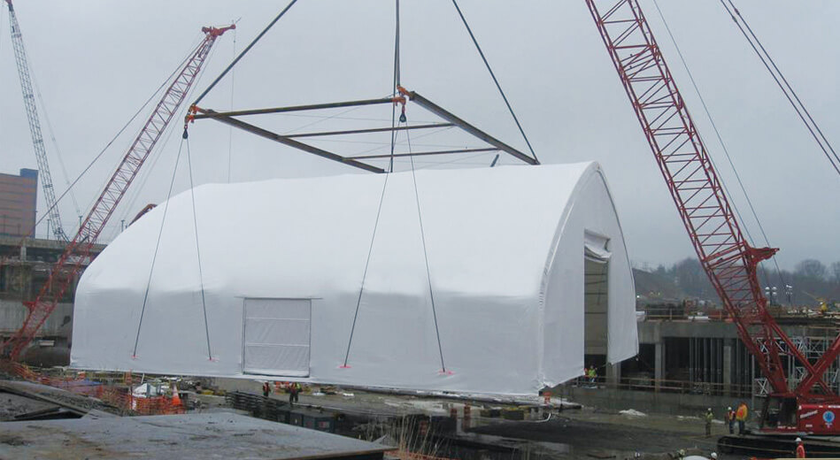 Déplacement d’un bâtiment en toile avec charpente d’acier galvanisé à l’aide de grues de chantier